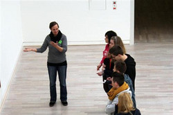Blick von oben auf den Austausch zwischen einer Studierenden und den SchülerInnen vor einem Kunstwerk