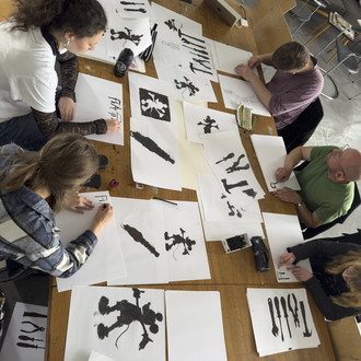 Studierende sitzen um einen Tisch und zeichnen