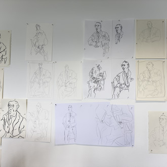 abstrahierte Zeichnungen einer sitzenden Person, an die Wand gepinnt