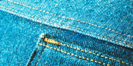 Nahaufnahme eines blauen Jeansstoffes mit gelben Nähten und sichtbaren Details einer Tasche.