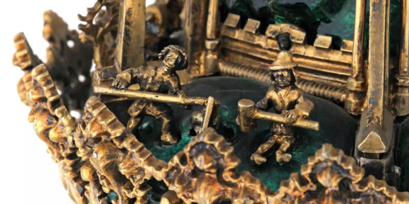 Detail einer vergoldeten Skulptur mit kleinen Figuren, die mit Hämmern arbeiten
