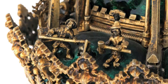 Detail einer vergoldeten Skulptur mit kleinen Figuren, die mit Hämmern arbeiten