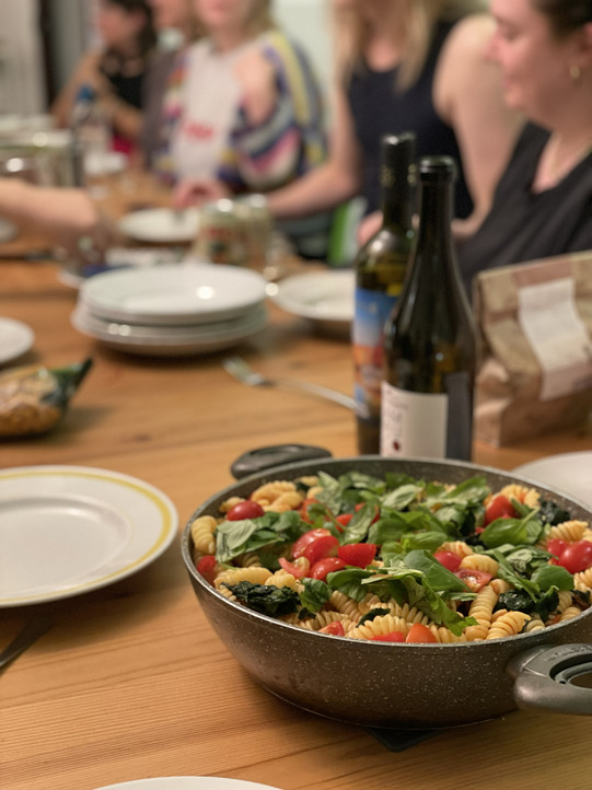 Studierende beim gemeinsames Essen, im Vordergrund eine Schüssel Nudelsalat mit Rucola.