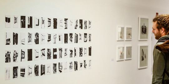 Ausstellung kleine Drucke Ein Mann betrachtet kleine Drucke an der Wand in einer Ausstellung.